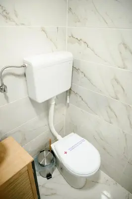 a white toilet in a bathroom with marble walls at CROWNE Stan11550 Sopstveno Parking Mesto in Lazarevac