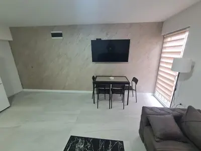 a living room with a table and chairs and a flat screen tv at Marash apartman 2 in Belgrade