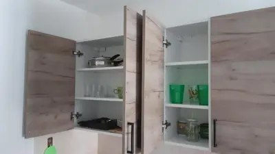 a kitchen with a wooden door and shelves at Apartman Toki, Aranđelovac in Arandjelovac