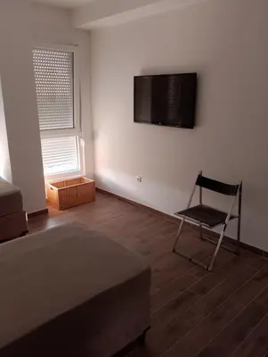 a bedroom with a bed and a chair and a television on the wall at Amare in Inđija