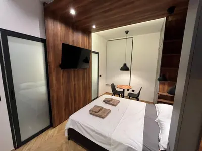 a bedroom with a bed and a tv and a table at Riverside Heritage Lux and Modern in Sajmište