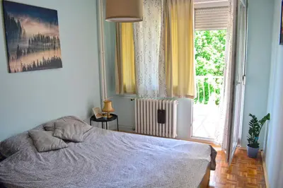 a bedroom with a bed and a large window at Dorcol Downtown Sunset in Belgrade