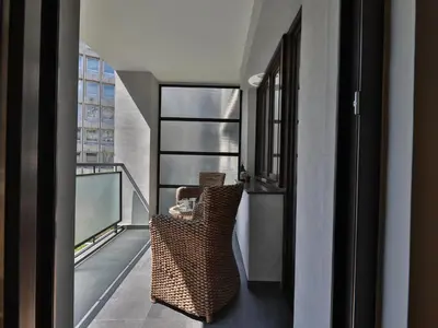 a balcony with a rattan chair and a window at Palace Apartment City Center in Belgrade