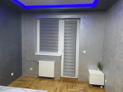 a bedroom with a window with a blue light at Crystal Apartman Obrenovac in Obrenovac
