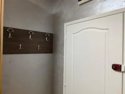 a bathroom with a white cabinet with hooks on the wall at Crystal Apartman Obrenovac in Obrenovac