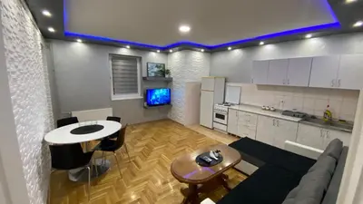 a kitchen and a living room with a couch and a table at Crystal Apartman Obrenovac in Obrenovac
