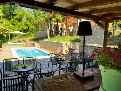 a patio with a table and chairs and a pool at Šumska Vila Lipovica in Barajevo