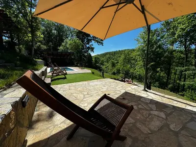 a chair sitting under an umbrella on a patio at Šumska Vila Lipovica in Barajevo
