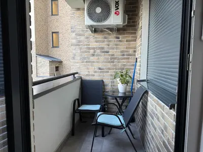 a balcony with a table and chairs and a fan at Apartman Lukač in Belgrade
