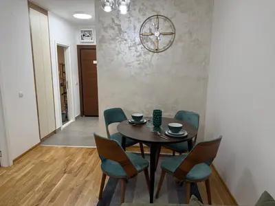 a dining room with a table and chairs and a clock at Apartman Lukač in Belgrade
