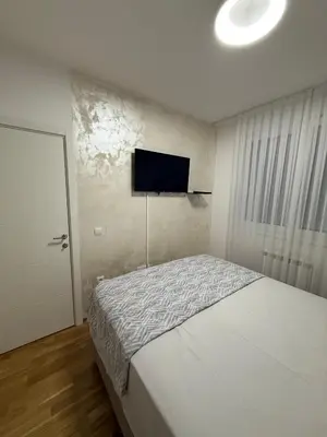 a bedroom with a bed and a flat screen tv on the wall at Apartman Lukač in Belgrade