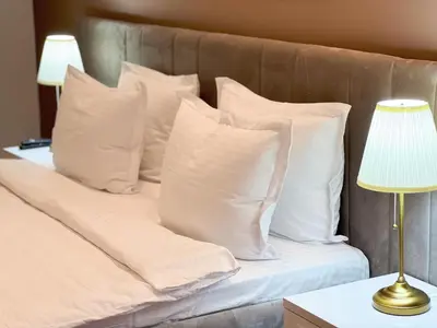 a bed with white pillows and a table with a lamp at Cetinjska Palace in Belgrade