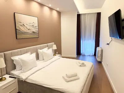 a bedroom with a bed with white sheets and a television at Cetinjska Palace in Belgrade