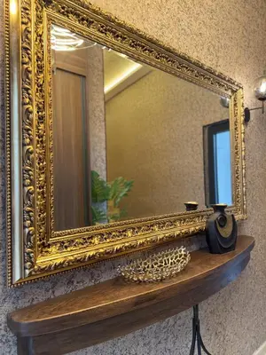 an ornate gold mirror on a wall with a wooden shelf at Cetinjska Palace in Belgrade