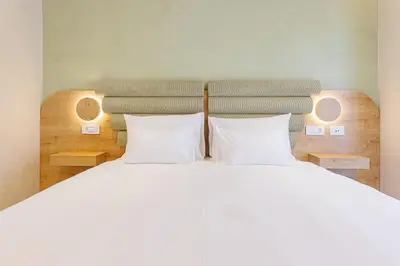 a bedroom with a white bed with two pillows at Hotel HOGO in Inđija