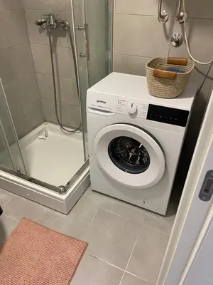 a washing machine in a bathroom with a shower at Fin apartman in Zvezdara