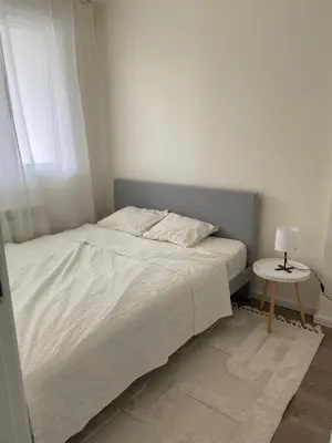 a bedroom with a white bed and a table at Fin apartman in Zvezdara