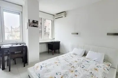 a bedroom with a bed and a desk and a window at All you need is just around the corner in Belgrade
