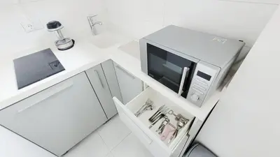 a white kitchen with a microwave on a counter at All you need is just around the corner in Belgrade