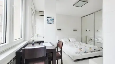 a bedroom with a bed and a desk and a table and chairs at All you need is just around the corner in Belgrade