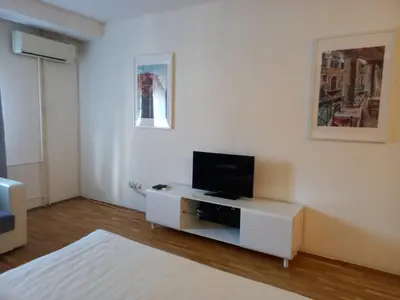 a white living room with a tv on a cabinet at Kiki in Belgrade