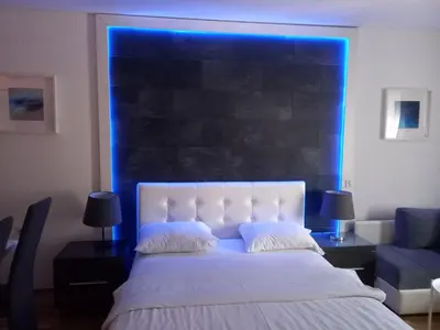 a bedroom with a white bed with a blue light at Kiki in Belgrade