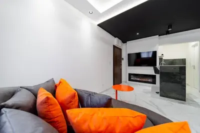 a living room with a gray couch and orange pillows at Dark Nest 3 Belgrade Apartments in Zvezdara