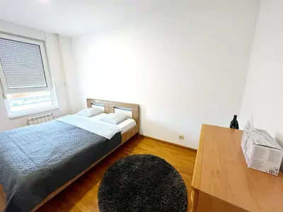 a bedroom with a bed and a window and a rug at Apartment B5 in Belgrade