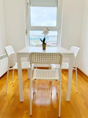 a white table with chairs and a vase of flowers on it at Apartment B5 in Belgrade