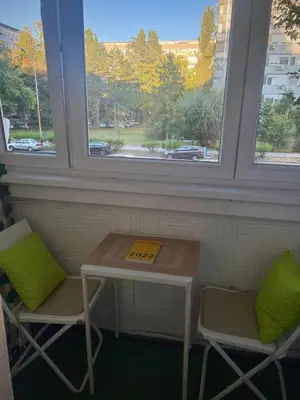 a table and two chairs in a room with two windows at Fontana cozy apartment near Danube river in Belgrade