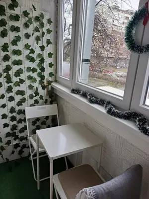 a table and a chair in a room with two windows at Fontana cozy apartment near Danube river in Belgrade