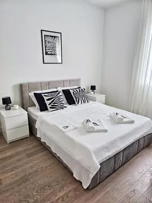 a bedroom with a large white bed with two night stands at ALPHA LUX - Galerija mall view - Beograd na vodi in Belgrade