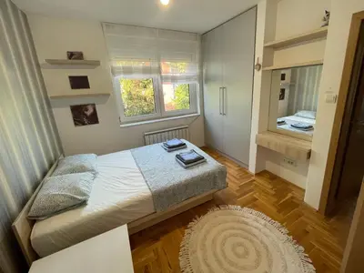 a small bedroom with a bed and a mirror at Comfy & Cozy Apartment - parking in Karaburma