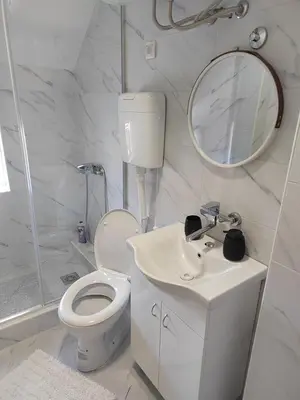 a white bathroom with a toilet and a mirror at Apartman Anđela in Jakovo