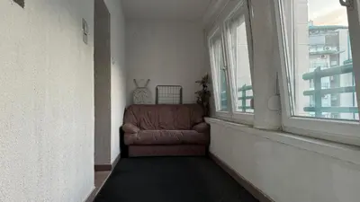 a brown chair sitting in a room with a window at Arena BGD - Hadrianz Apartment in Novi Beograd
