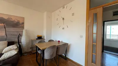 a dining room with a table and a clock on the wall at Arena BGD - Hadrianz Apartment in Novi Beograd