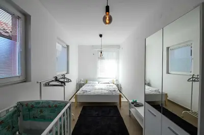a white room with a bed and a mirror at Paun Apartmani in Smederevo