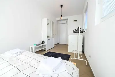 a white bedroom with a bed and a window at Paun Apartmani in Smederevo