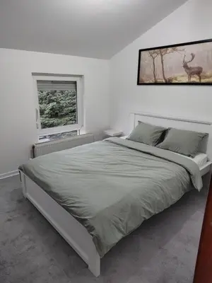 a white bedroom with a bed with a picture on the wall at Apartman Ingrid in Belgrade
