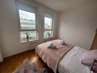a bedroom with two towels on a bed with two windows at Akacija - Belvil in Belgrade