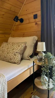 a bed in a wooden room with a table with a lamp at Luxury house Nena Fruška gora - kuća za odmor in Velika Remeta