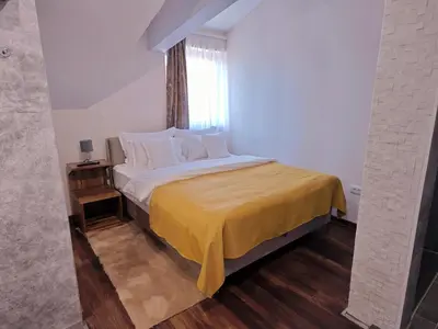 a bedroom with a bed with a yellow bedspread and a window at Green Land Club in Novi Banovci