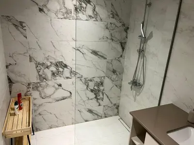 a bathroom with a shower with a marble wall at Aurora 011 in Sajmište