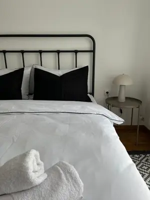 a bed with white sheets and pillows and a table at Apartman Resavska in Belgrade