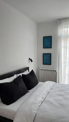 a white bed with black pillows in a bedroom at Apartman Resavska in Belgrade