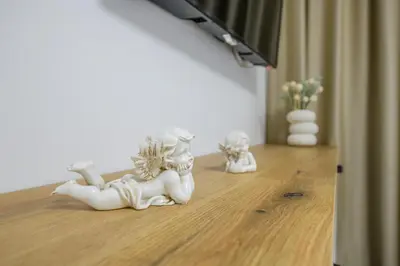 two white statues sitting on a wooden floor at NAŠ Apartman in Voždovac