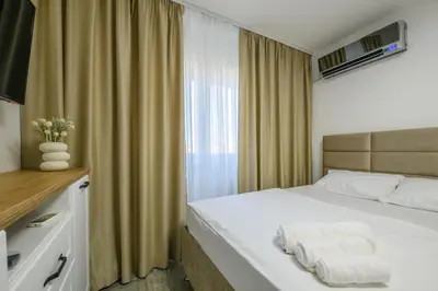 a bedroom with a white bed with a window at NAŠ Apartman in Voždovac