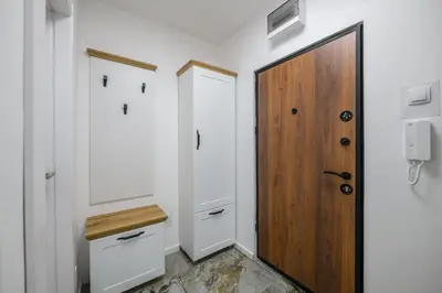 a bathroom with white walls and a wooden door at NAŠ Apartman in Voždovac