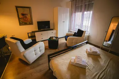 a living room with a bed and two chairs at Lina Apartments in Belgrade