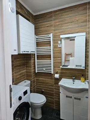 a bathroom with a toilet and a sink and a washing machine at Apartman Gaga in Batajnica